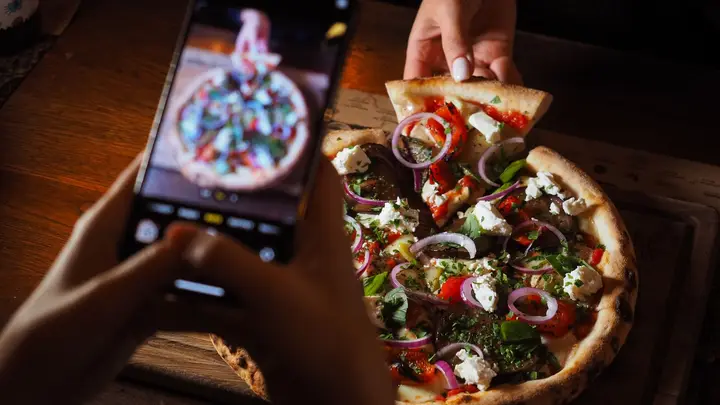 Pessoa fotografando uma pizza com o celular